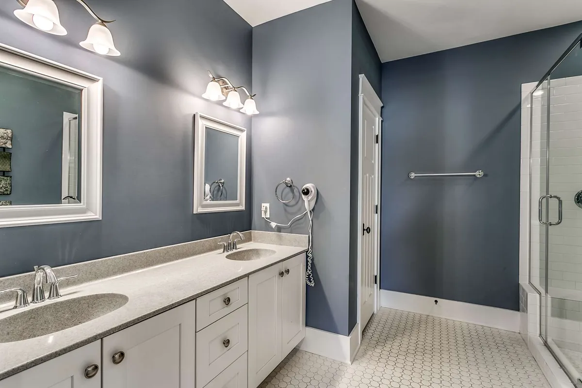 A modern bathroom with dual sinks, large mirrors, and a glass-enclosed shower. The space is bright, airy, and impeccably clean, offering a spa-like experience for guests starting or ending their day.
