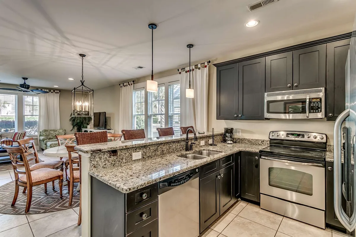 A spacious, sunlit kitchen with gleaming granite countertops, a large island perfect for gathering, modern pendant lighting, and premium stainless steel appliances. The space is inviting and designed for both casual meals and memorable family celebrations.